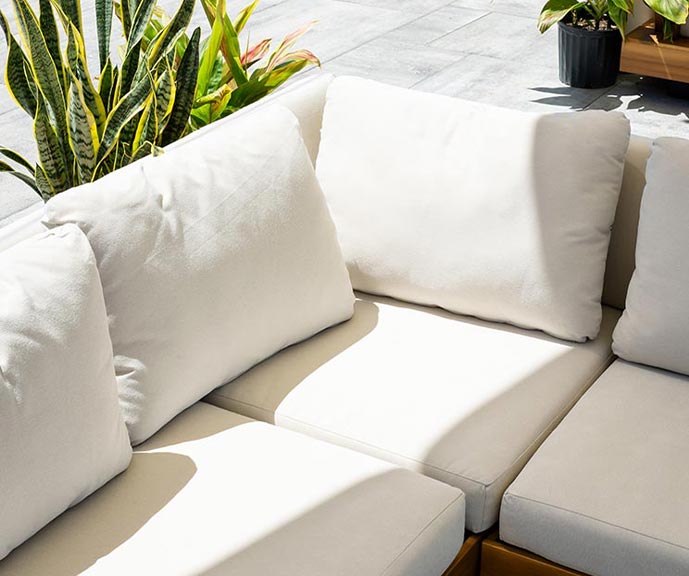 Cream-cushioned outdoor lounge seating surrounded by potted plants at The Brook Beer Garden.